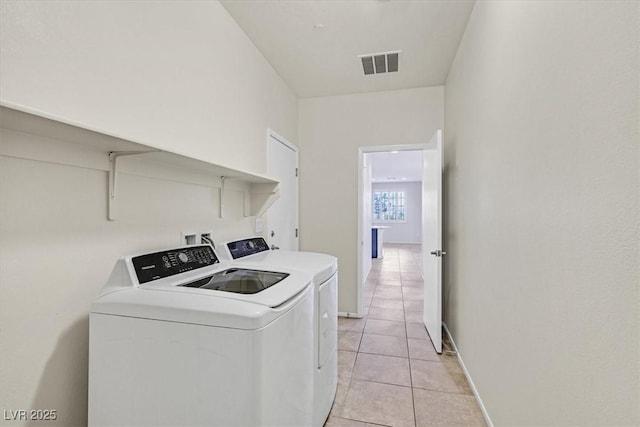 clothes washing area with baseboards, visible vents, laundry area, light tile patterned flooring, and washer and clothes dryer