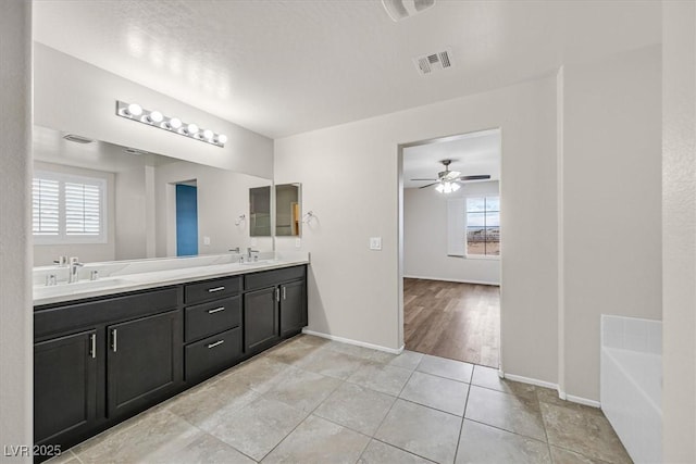 bathroom featuring visible vents, double vanity, a sink, tile patterned floors, and a bath