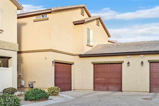 exterior space featuring stucco siding, a tiled roof, and a garage