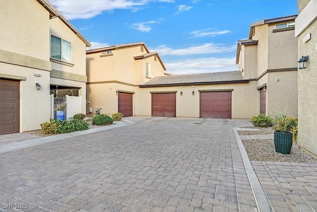 exterior space with a gate, decorative driveway, and stucco siding