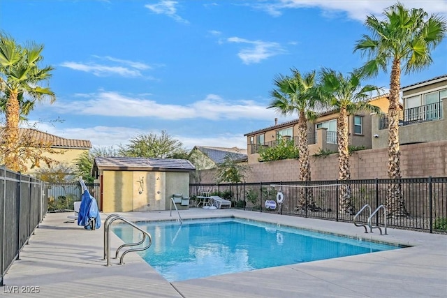 community pool featuring a storage shed, an outdoor structure, fence, and a patio