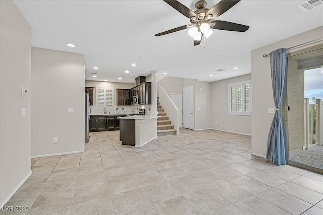 kitchen featuring visible vents, freestanding refrigerator, light countertops, dark brown cabinetry, and open floor plan