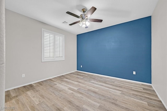 unfurnished room featuring baseboards, wood finished floors, visible vents, and ceiling fan