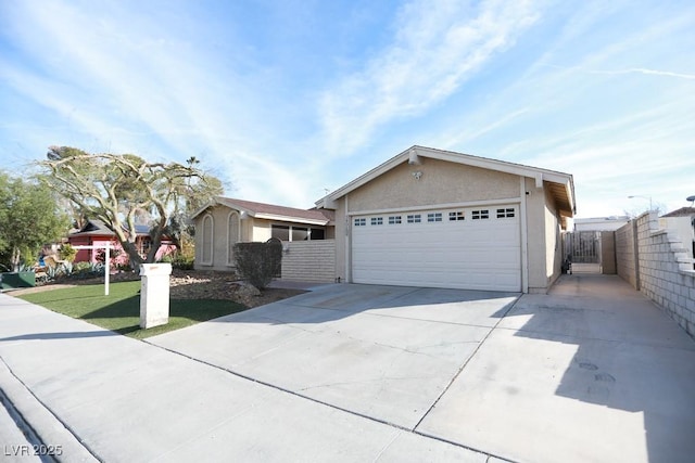 ranch-style home with an attached garage, fence, a front yard, stucco siding, and driveway