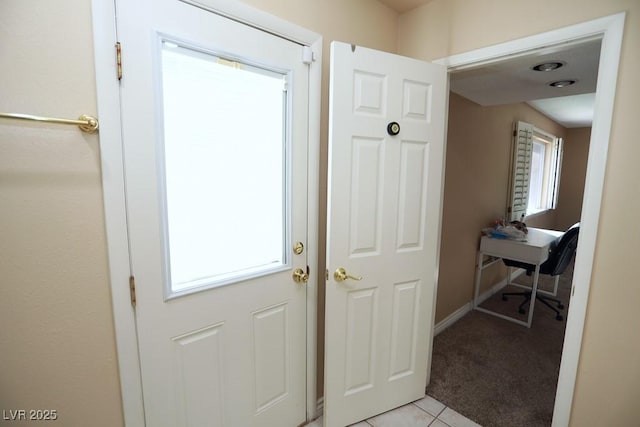 doorway featuring light tile patterned floors, baseboards, plenty of natural light, and light carpet