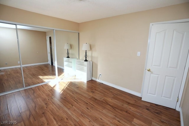 unfurnished bedroom with a closet, baseboards, and wood-type flooring