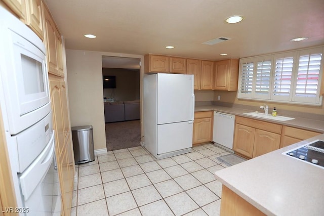 kitchen featuring a sink, visible vents, white appliances, and light brown cabinetry