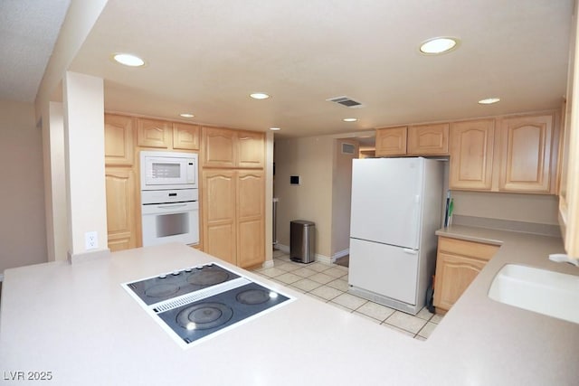 kitchen featuring white appliances, light brown cabinets, light tile patterned flooring, a sink, and light countertops