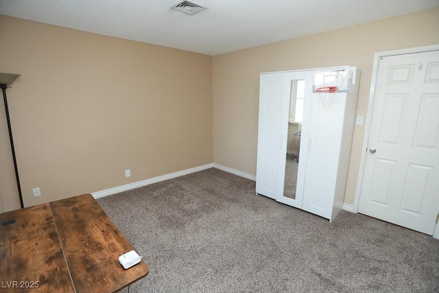 unfurnished bedroom with visible vents, a textured ceiling, baseboards, and carpet