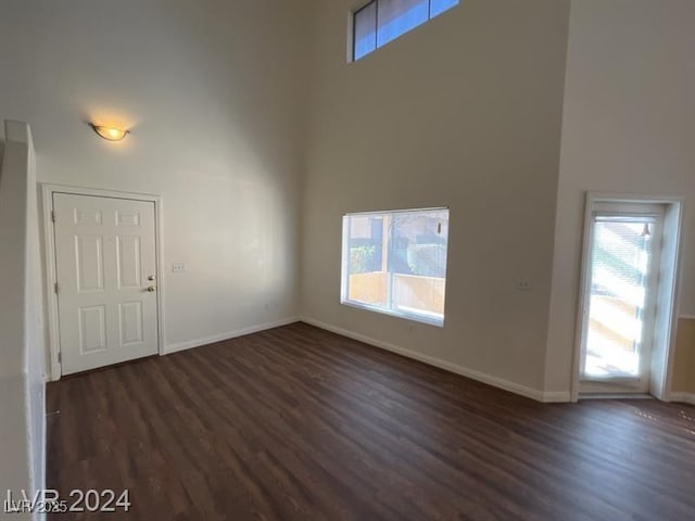 unfurnished room featuring dark wood-type flooring, a high ceiling, and plenty of natural light