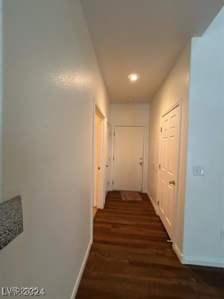 corridor with baseboards and dark wood-style flooring