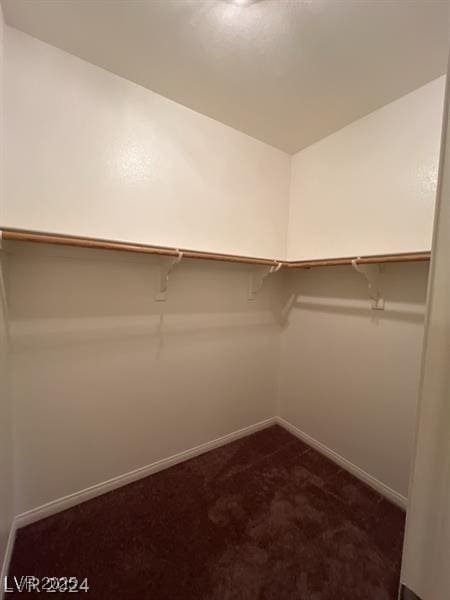 walk in closet featuring lofted ceiling and dark colored carpet