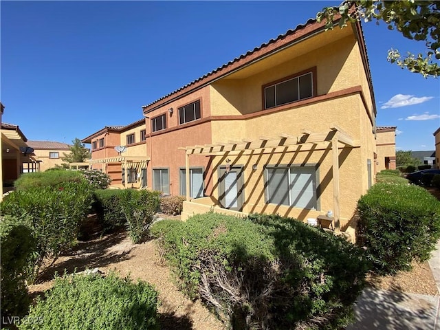 rear view of property with a tiled roof and stucco siding