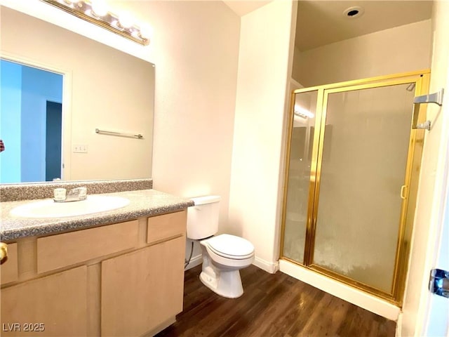 bathroom with baseboards, toilet, a stall shower, wood finished floors, and vanity