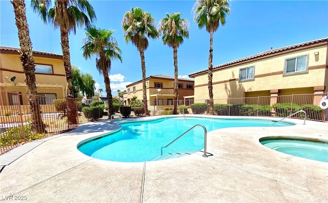 pool with a residential view, a community hot tub, and fence