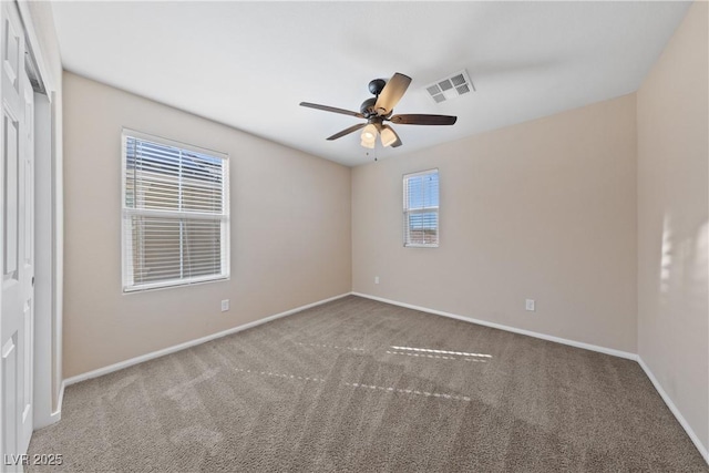 carpeted spare room with visible vents, baseboards, and ceiling fan