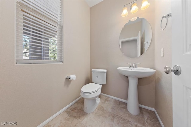 half bath featuring a sink, baseboards, and toilet