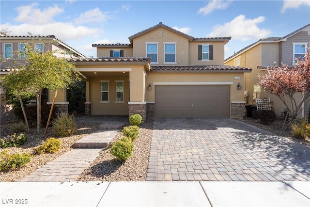 mediterranean / spanish-style home featuring decorative driveway, stone siding, an attached garage, and stucco siding