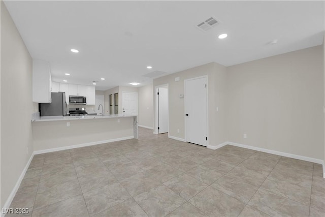 unfurnished living room with a sink, visible vents, baseboards, and recessed lighting