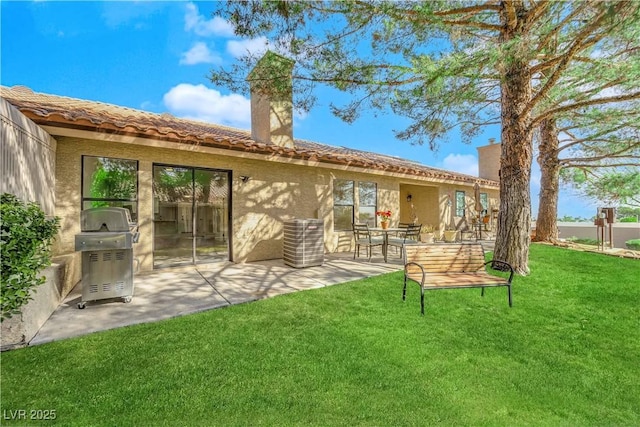 back of property with a yard, a patio, and stucco siding