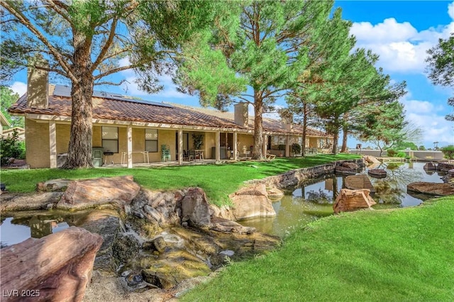 7803 Canoe Ln, Las Vegas, NV 89145 - back of property with a chimney, roof mounted solar panels, a tiled roof, and a yard