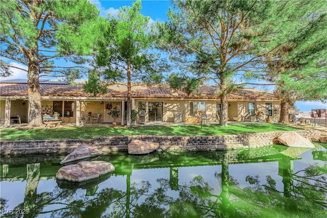 rear view of house with a patio, solar panels, stucco siding, a tile roof, and a lawn