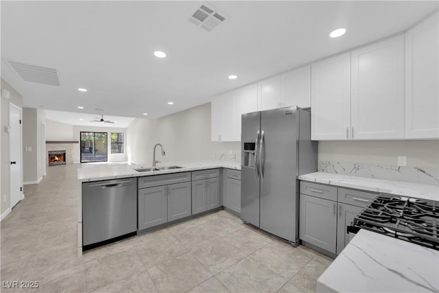 kitchen with visible vents, gray cabinets, a sink, stainless steel appliances, and a peninsula