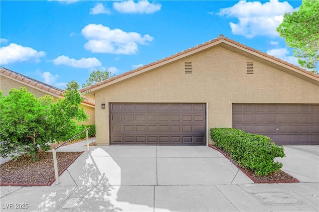 exterior space with a tiled roof, stucco siding, driveway, and an attached garage