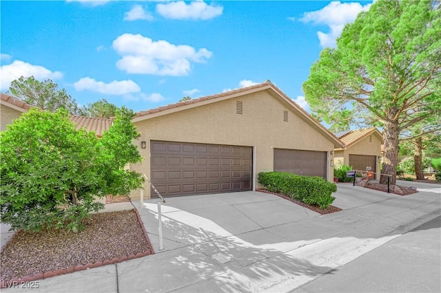 view of front of home with concrete driveway, a tiled roof, and stucco siding