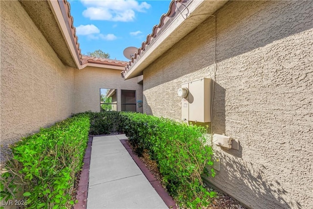 view of side of home with a tiled roof and stucco siding