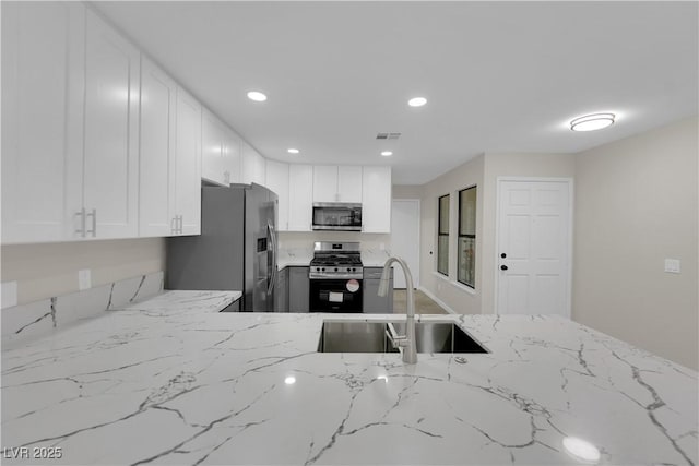 kitchen featuring light stone counters, recessed lighting, a sink, stainless steel appliances, and white cabinets