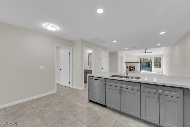 kitchen with a sink, stainless steel dishwasher, gray cabinetry, and a tile fireplace