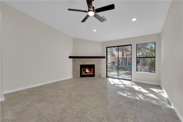 unfurnished living room with a tiled fireplace, recessed lighting, baseboards, and ceiling fan