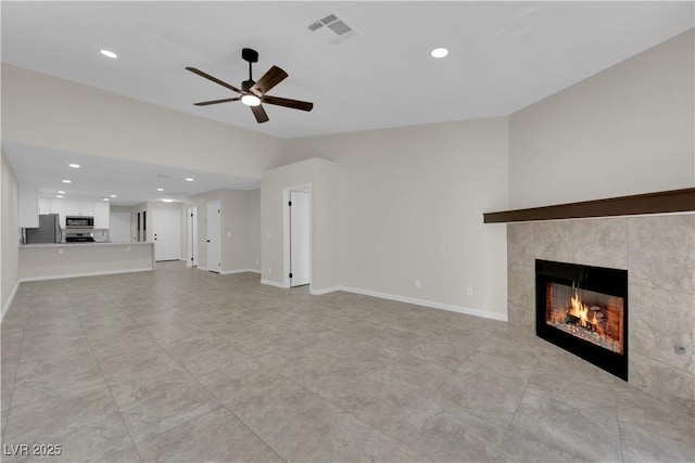 unfurnished living room with visible vents, a tile fireplace, lofted ceiling, and baseboards