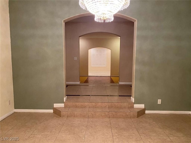 staircase featuring a chandelier, tile patterned flooring, arched walkways, and baseboards