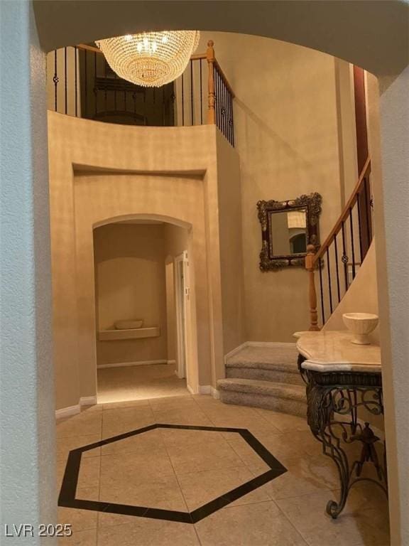 hallway featuring tile patterned flooring, stairway, an inviting chandelier, and baseboards