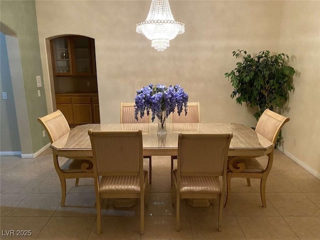 dining area with light tile patterned floors, arched walkways, baseboards, and a chandelier