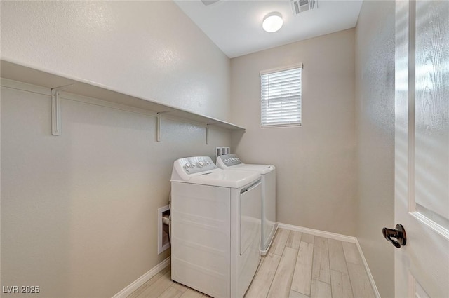 clothes washing area featuring visible vents, independent washer and dryer, light wood-style flooring, baseboards, and laundry area