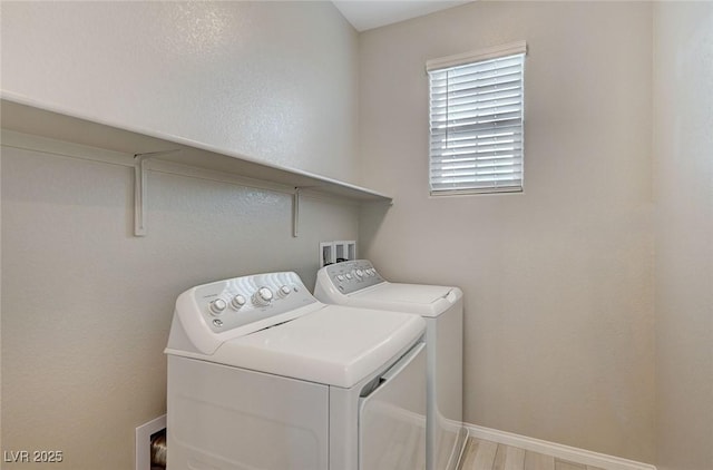 laundry room featuring laundry area, washing machine and dryer, light wood-style flooring, and baseboards