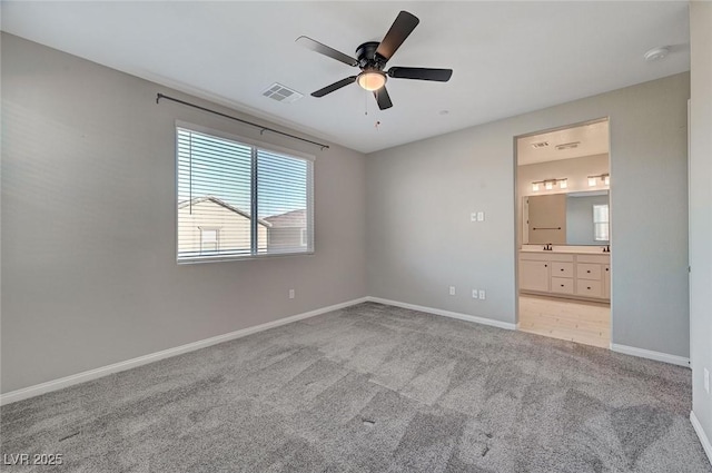 unfurnished bedroom with visible vents, baseboards, carpet, ensuite bath, and a ceiling fan