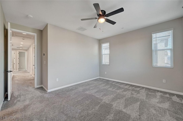 carpeted spare room with visible vents, baseboards, and ceiling fan