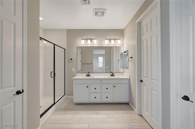 bathroom with visible vents, wood finish floors, double vanity, a stall shower, and a sink