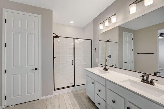 full bath featuring a shower stall, wood finish floors, and a sink