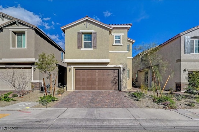 view of front facade with stucco siding, an attached garage, a tile roof, and decorative driveway