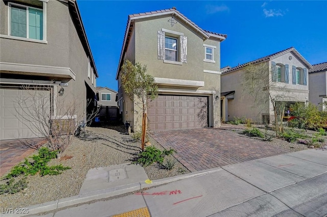 view of front of house featuring stucco siding, decorative driveway, an attached garage, and a tile roof