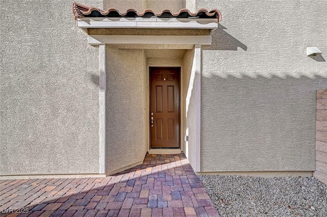 doorway to property with stucco siding and a tiled roof