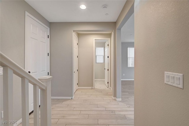 hallway featuring stairway, baseboards, and wood finish floors