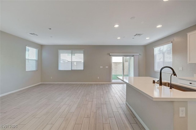 kitchen with visible vents, open floor plan, light countertops, light wood-style flooring, and white cabinets