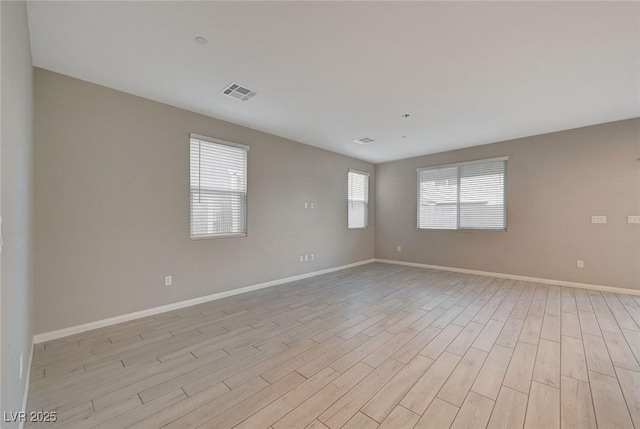 spare room featuring visible vents, baseboards, and light wood-style flooring