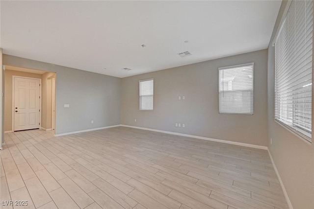 unfurnished room featuring visible vents, plenty of natural light, and light wood-style floors